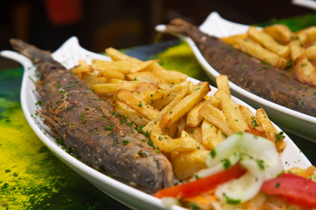 Close-up of a savory fish and chips dish garnished with fresh herbs, highlighting traditional flavors.